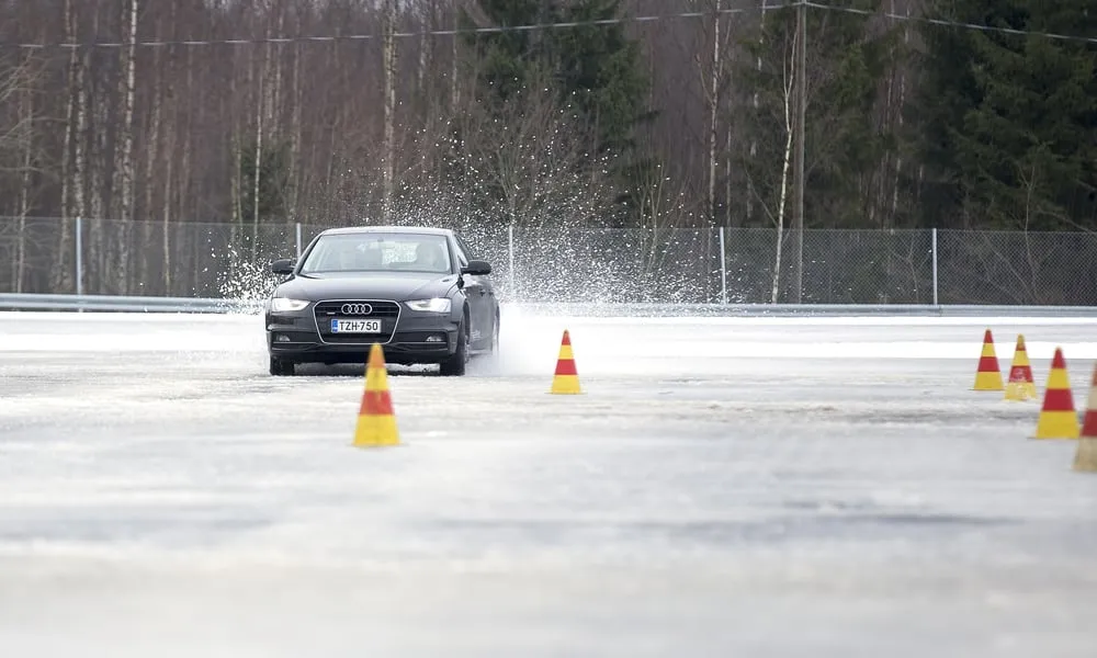 Bil på halkbana med koner på isigt underlag